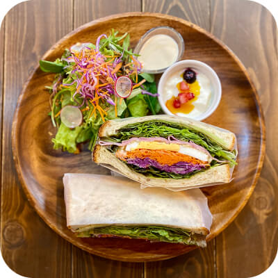 写真：木の器にサンドイッチとサラダとヨーグルトがのっています