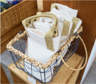 工房尾道帆布のオリジナルトートバッグがかごに並べられています