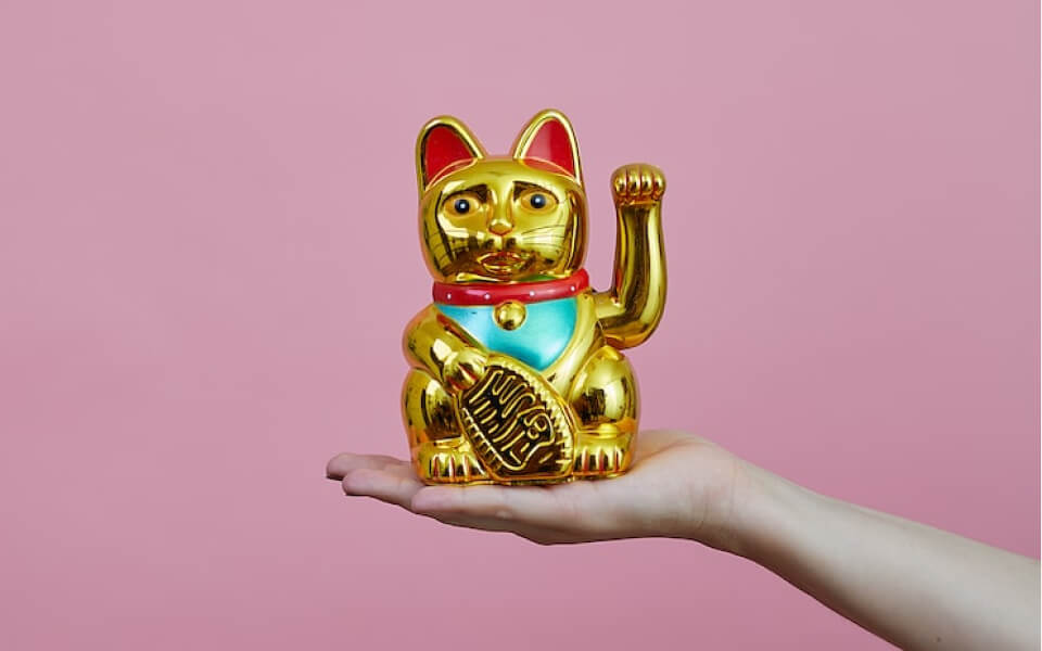 手の上に金色の招き猫が乗っています