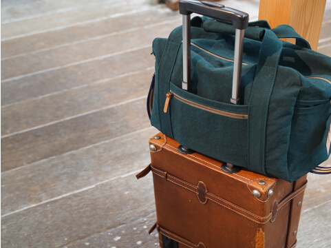 キャリーバッグに緑色のカバンが乗っています